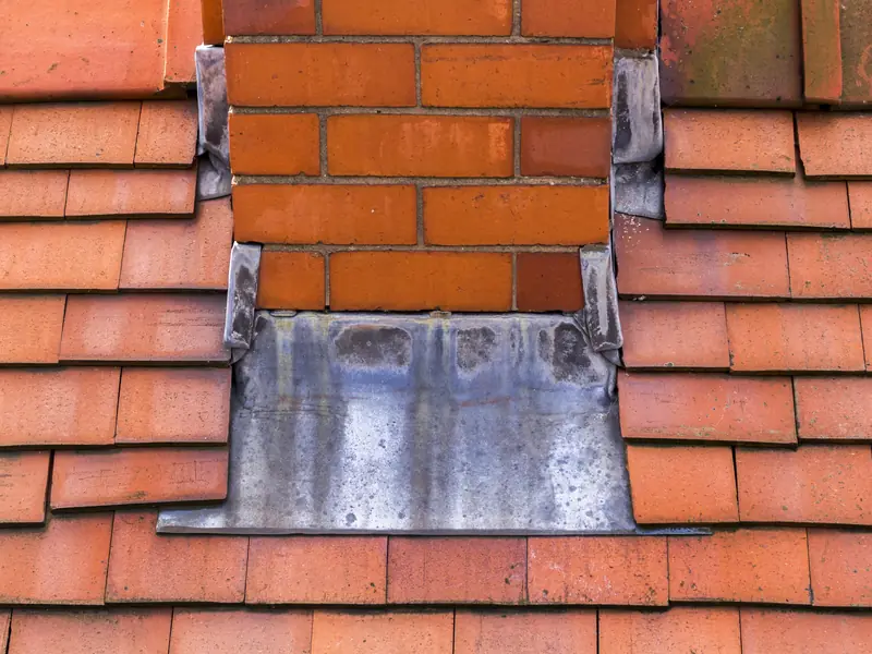 Lead flashing at the base of a chimney on a tiled roof