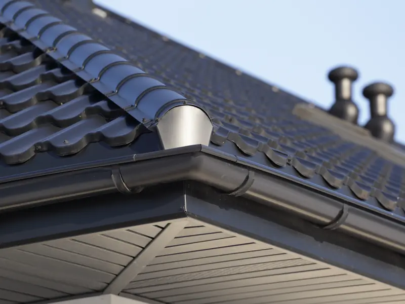 Dark grey gutter along the edge of a tiled roof