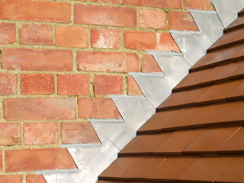Stepped lead flashing where a tiled roof meets a brick wall